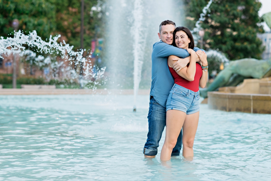 An engaged couple hold each other while standing in Swann Memorial Fountain.